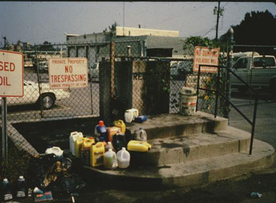Photo showing bottles of household chemicals and oil spills located in a parking area.