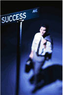 Graphic depicts a businessman looking up at a street sign named "Success Avenue."